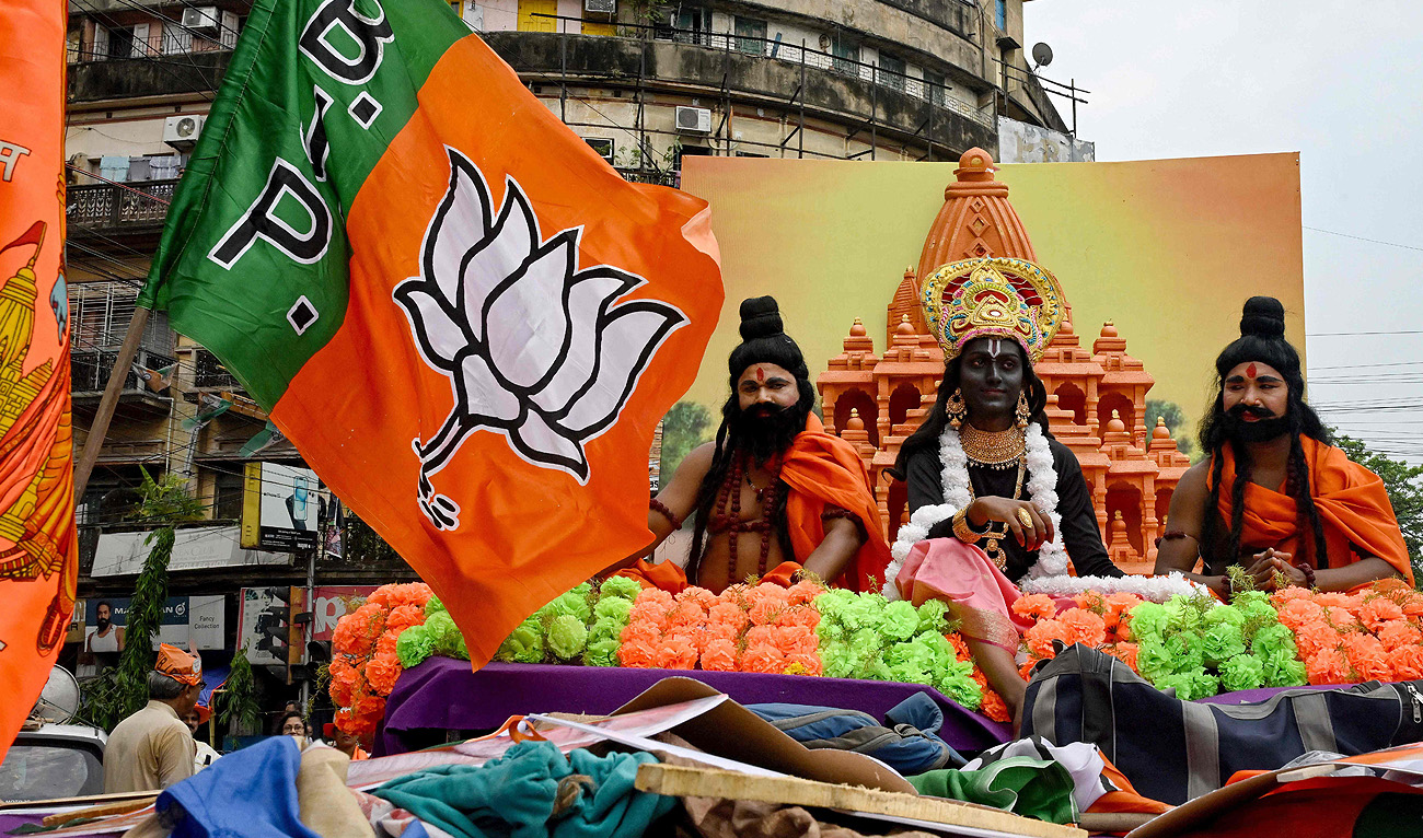 Activists of the ruling Bharatiya Janata Party (BJP) dressed as Hindu mythological characters sit opposite a banner picturing the Ram temple of Ayodhya, during a campaign rally in Kolkata on May 10, 2024, ahead of the fourth phase of voting of India’s general election. (AFP/File)