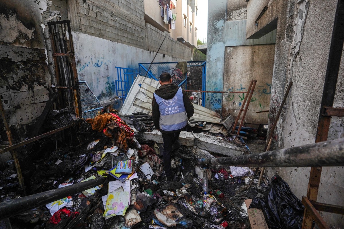 A UNRWA personnel checks a burnt area at a school housing displaced Palestinians that was hit during the ongoing conflict between Israel and the militant group Hamas, in Nuseirat in the central Gaza Strip on May 17, 2024. (AFP)