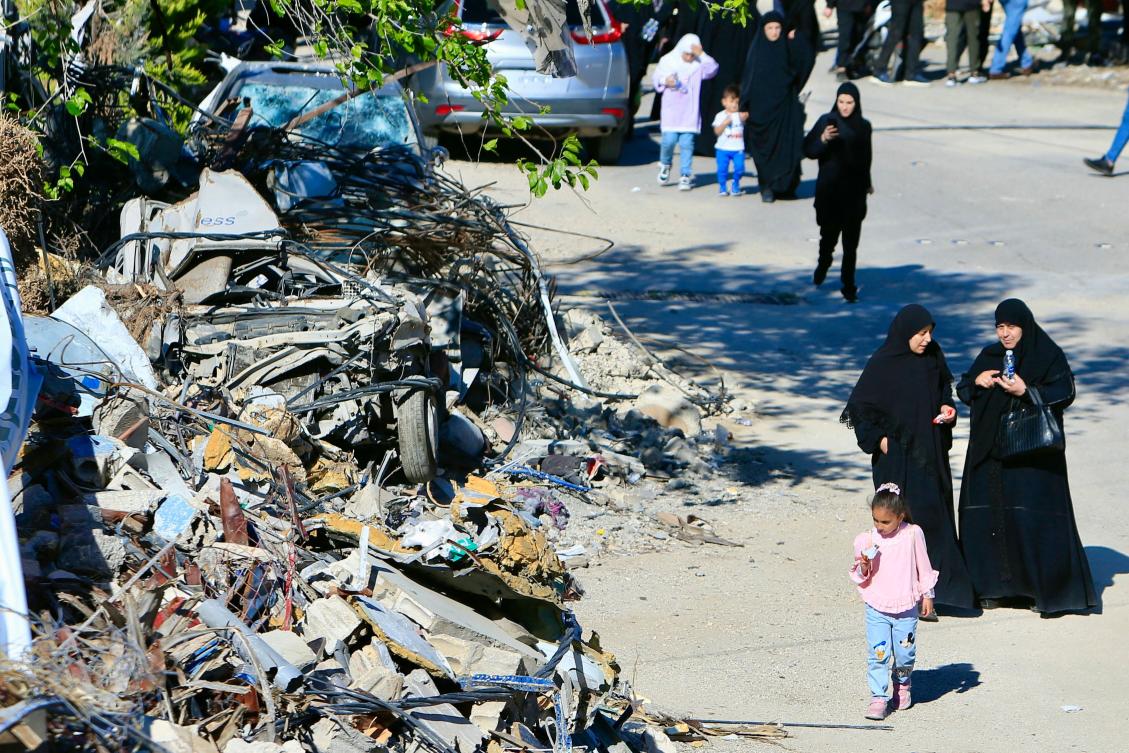Women walk past the rubble of a building destroyed by Israeli bombardment after attending the funeral of a Hezbollah militant killed in an Israeli strike in the southern Lebanese village of Meis Al-Jabal. (AFP)