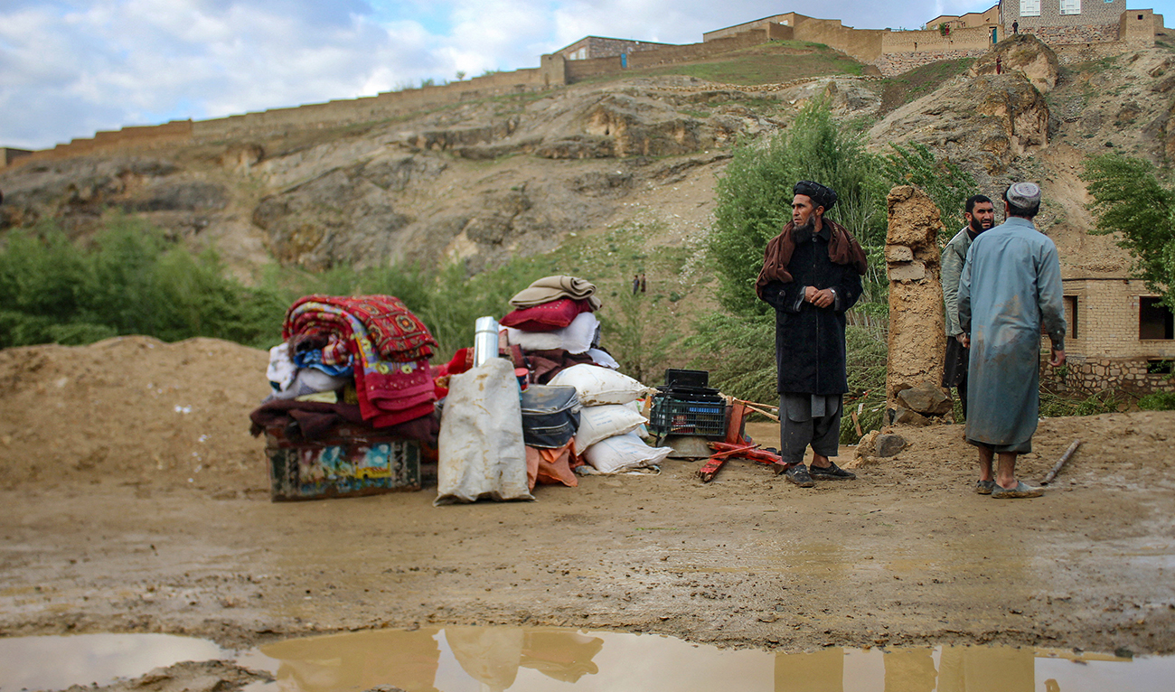 Afghan men stand beside their belongings kept near a damaged house after flash floods following heavy rainfall in Firozkoh, Ghor province on May 18, 2024. (AFP)