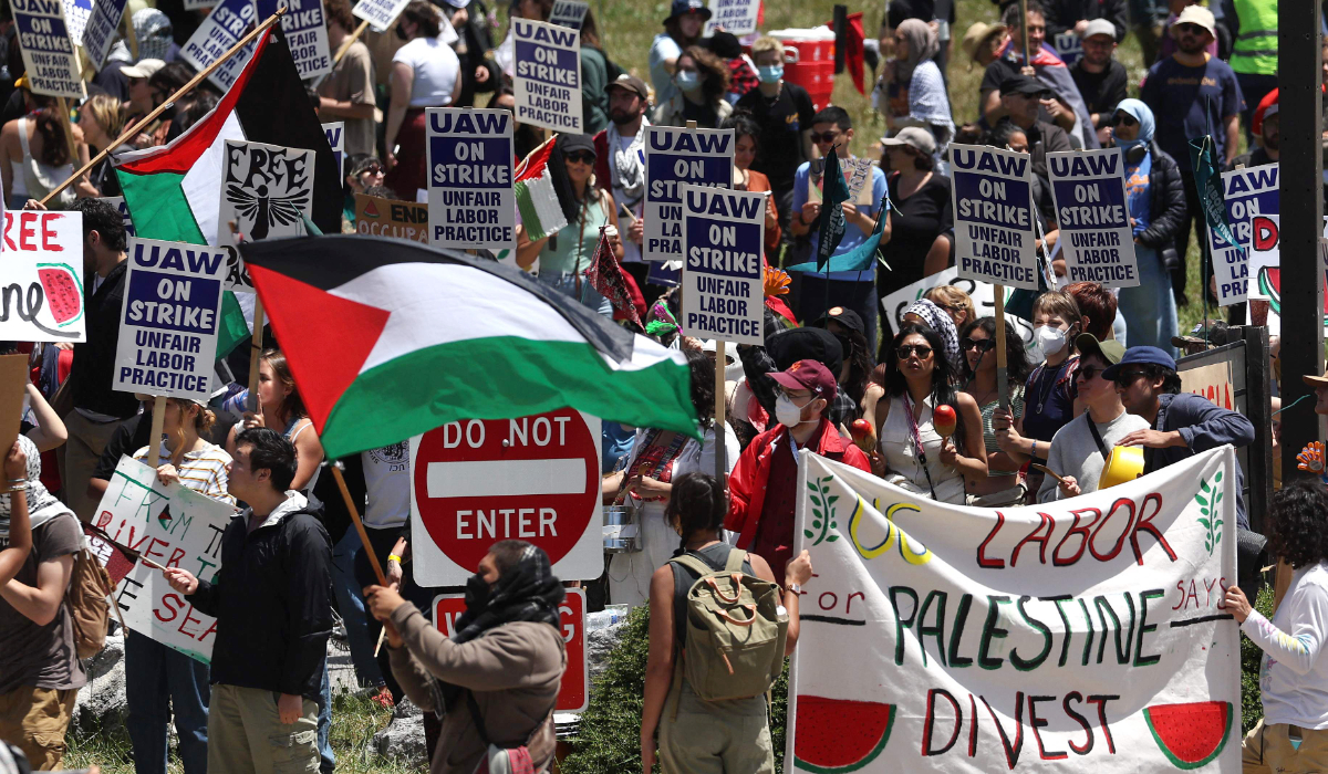 U.C. Santa Cruz workers who are union members of U.A.W. 4811, which is part of the United Auto Workers, and pro-Palestinian protesters carry signs as they demonstrate in front of the U.C. Santa Cruz campus on May 20, 2024 in Santa Cruz, California. (AFP)
