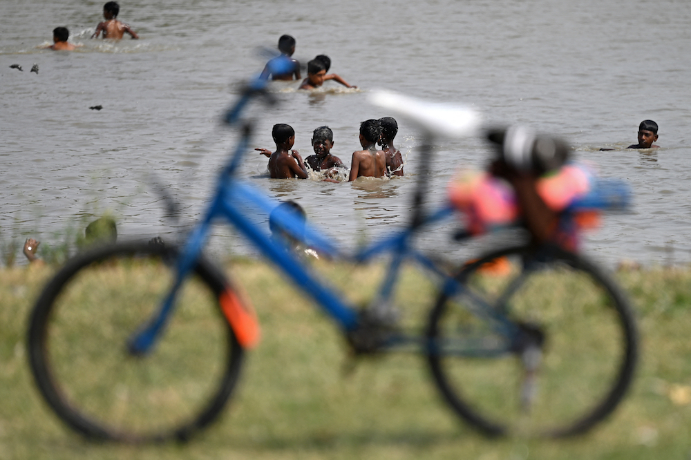 Heatwaves, most likely fueled by climate change, have been reaching dangerous levels across India and other Asian countries since April. Boys cool themselves in a pond on a hot summer day in New Delhi on May 5, 2024. (AFP)
