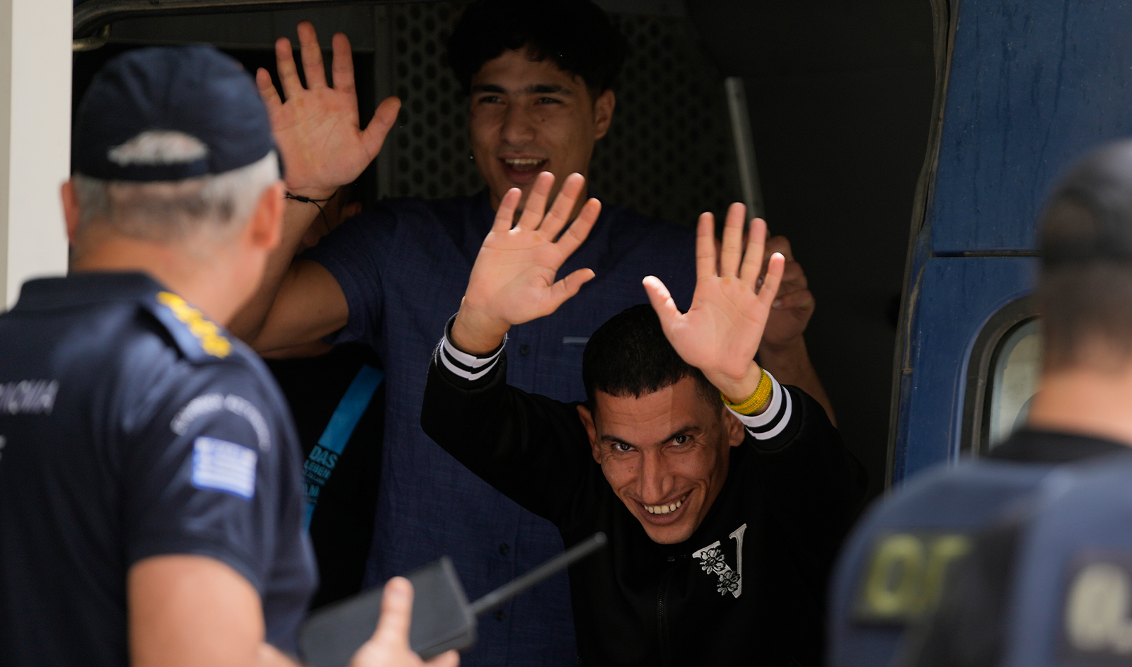 Two of nine Egyptians, who were on trial for migrant smuggling, wave to the media persons as they leave the court in Kalamata, southwestern Greece, on May 21, 2024. (AP)