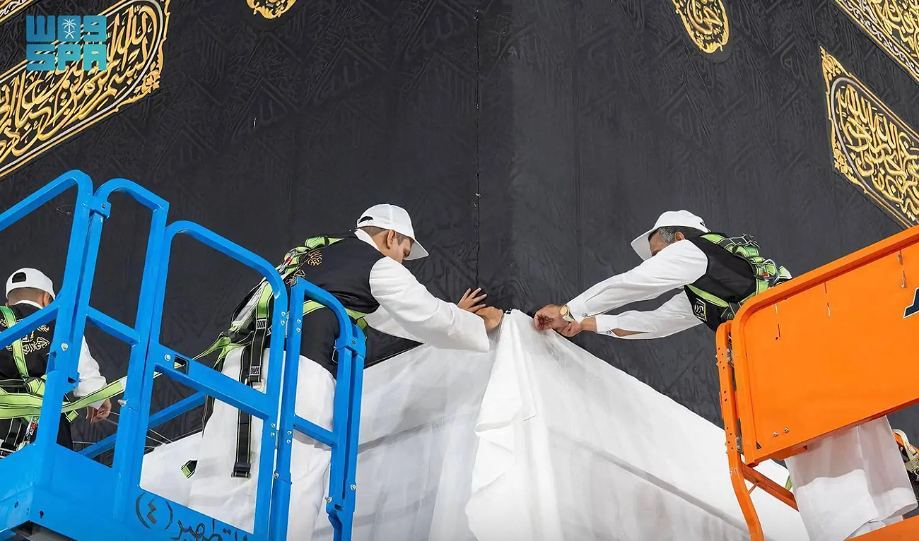 In this handout photograph, taken and released by Saudi Press Agency, specialized technicians are seen at work at the Kaaba in Makkah on May 23, 2024, raising the special cover to keep it from being soiled and damaged ahead of the annual Hajj pilgrimage. (SPA)