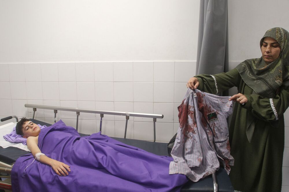 The aunt of 11-year-old Lebanese school boy Mohammad Ali Nasser shows his shirt covered with blood at the General Hospital in Nabatieh, following his injury during an Israeli drone strike on the car of a Hezbollah fighter in southern Lebanon on May 24, 2024. (AFP)