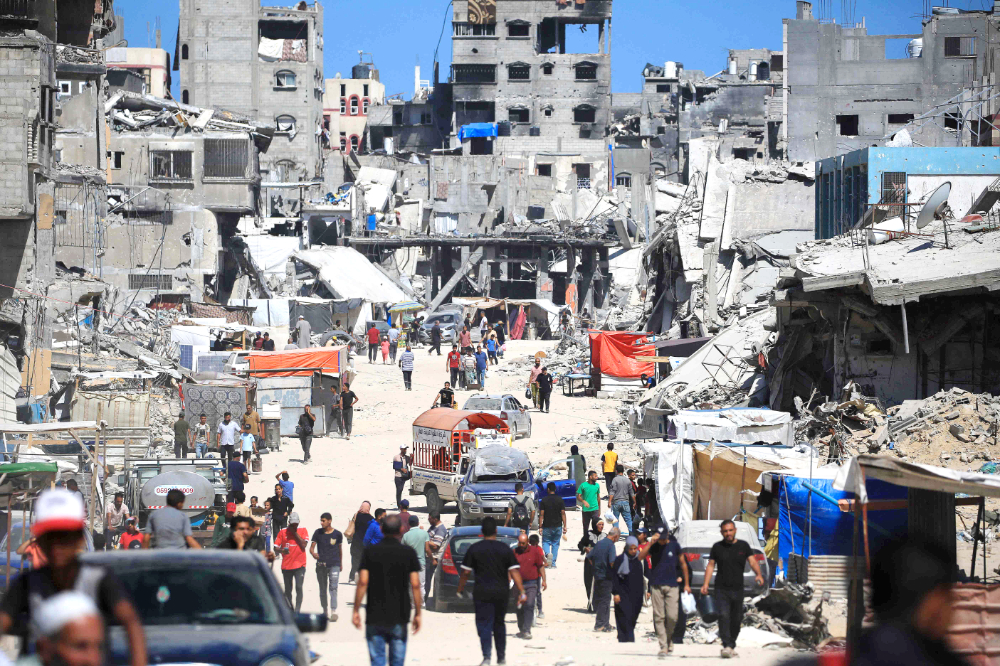 Displaced Palestinians walk along a devastated street in Khan Younis in the southern Gaza Strip on Friday as conflict between Israel and Hamas continues. (AFP)