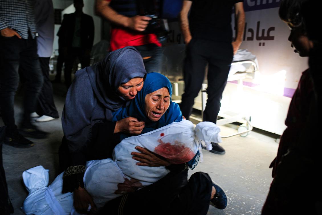 A Palestinian woman holds the shrouded body of a child killed in Israeli bombardment in Tel Al-Sultan in Rafah of the southern Gaza Strip on May 26, 2024. (AFP)