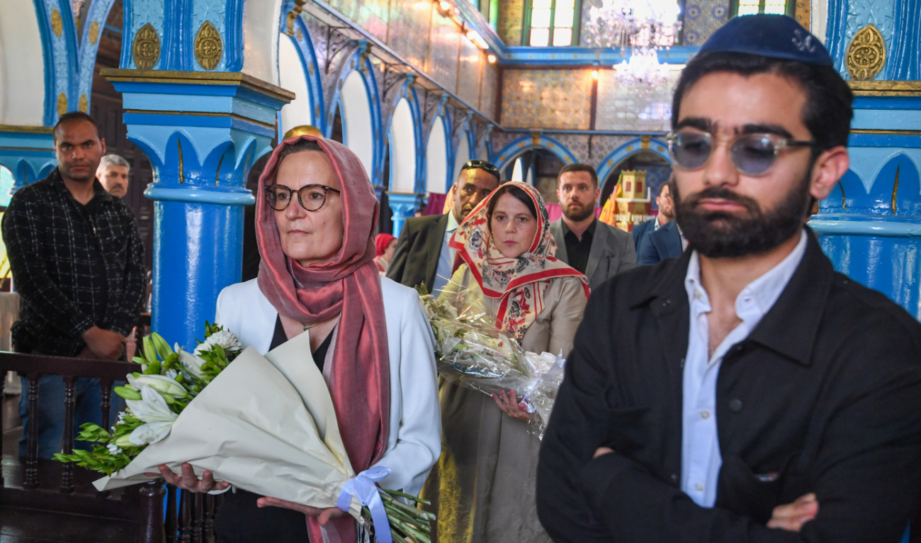 French ambassador to Tunisia Anne Gueguen (Centre-L) and US Deputy Chief of Mission Natasha Franceschi (C) carry flowers in memory of those killed in a mass shooting last year at the Ghriba synagogue in Djerba, during the second day of the annual Jewish pilgrimage on May 26, 2024. (AFP)