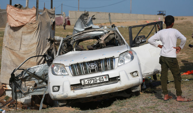 People gather around the carcass of a car used by US-based aid group World Central Kitchen, that was hit by an Israeli strike in the central Gaza Strip on April 2, 2024. (AFP/File)