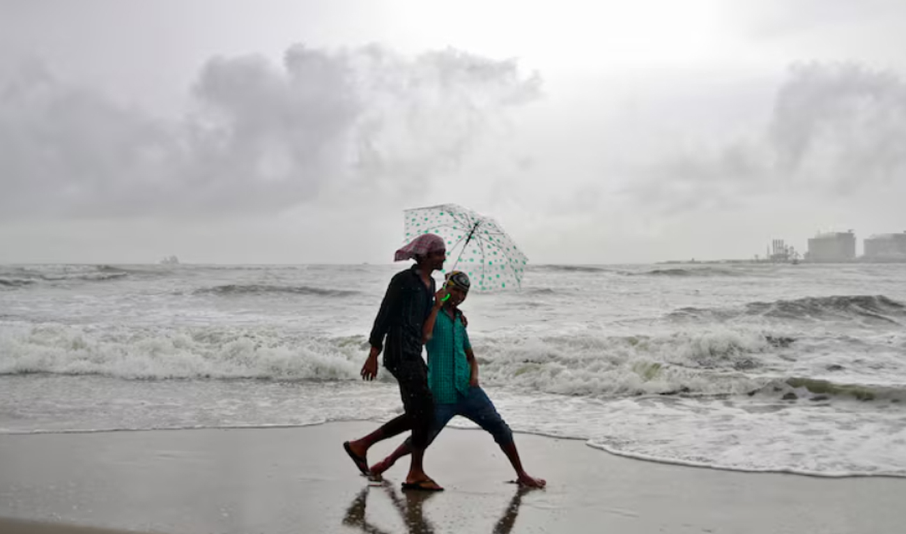 Beachgoers react to the camera while holding an umbrella as it drizzles at the Fort Kochi beach in the southern Indian city of Kochi June 6, 2014. (Reuters/File)
