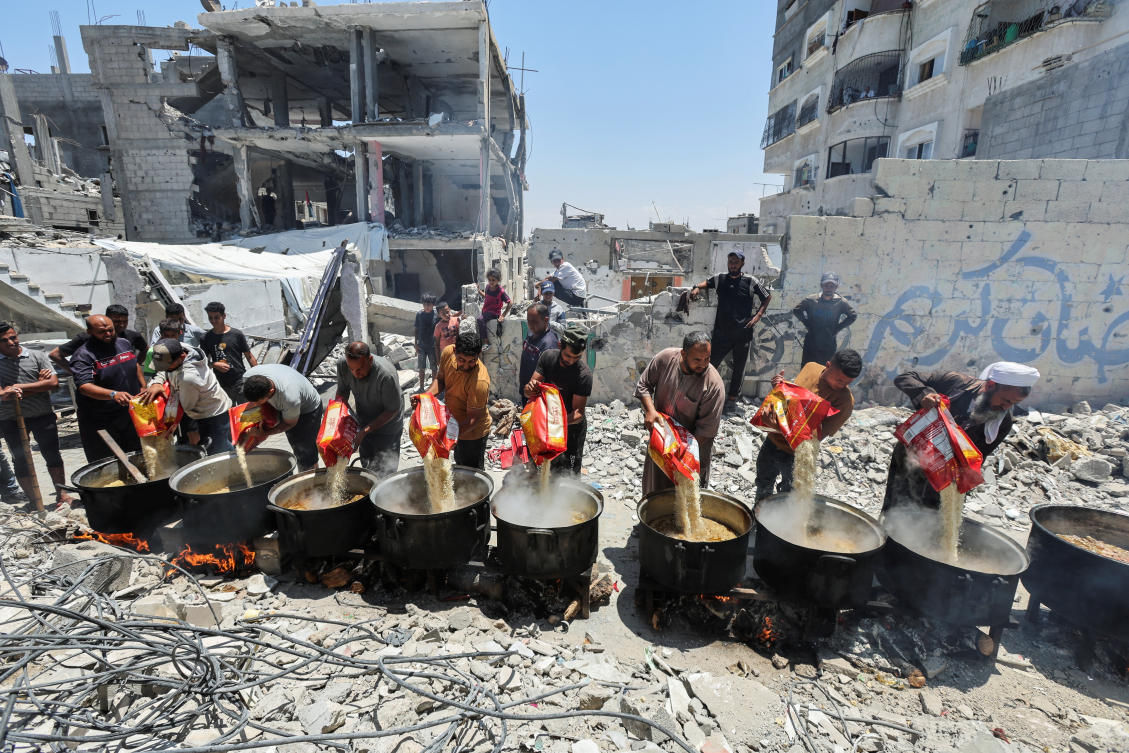 Palestinians cook food near houses destroyed in the Israeli military offensive, in Khan Younis in the southern Gaza Strip, May 30, 2024. (Reuters)