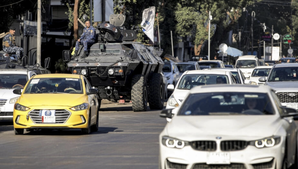 Motorists drive past Iraqi security forces' armoured vehicles in Baghdad on December 26, 2023. (AFP/File Photo)