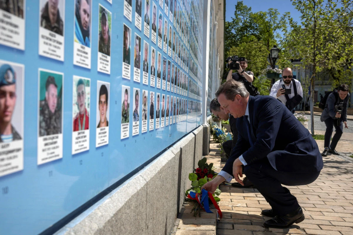 Britain's Foreign Secretary David Cameron and Ukrainian Foreign Minister Dmytro Kuleba lay flowers at a memorial wall to fallen servicemen outside St. Michael's Golden-Domed Monastery in Kyiv, on May 2, 2024. (AFP)
