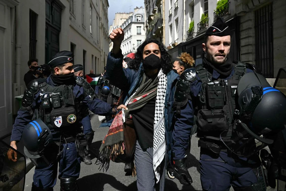 A protester is escorted away by French gendarmes during the evacuation of a pro-Gaza sit-in in the entrance hall of the Institute of Political Studies (Sciences Po Paris) in Paris. (AFP)