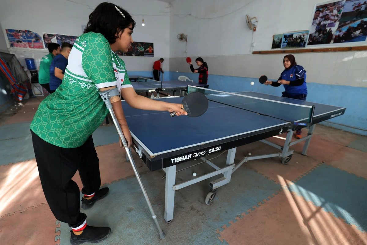 Iraqi paralympics table tennis athlete Najla Imad (L), trains at the Al-Mawaheb Club premises in Baquba, on Feb. 26, 2024. When car bomb survivor Najlah Imad first took up table tennis, her relatives warned against it. (AFP)
