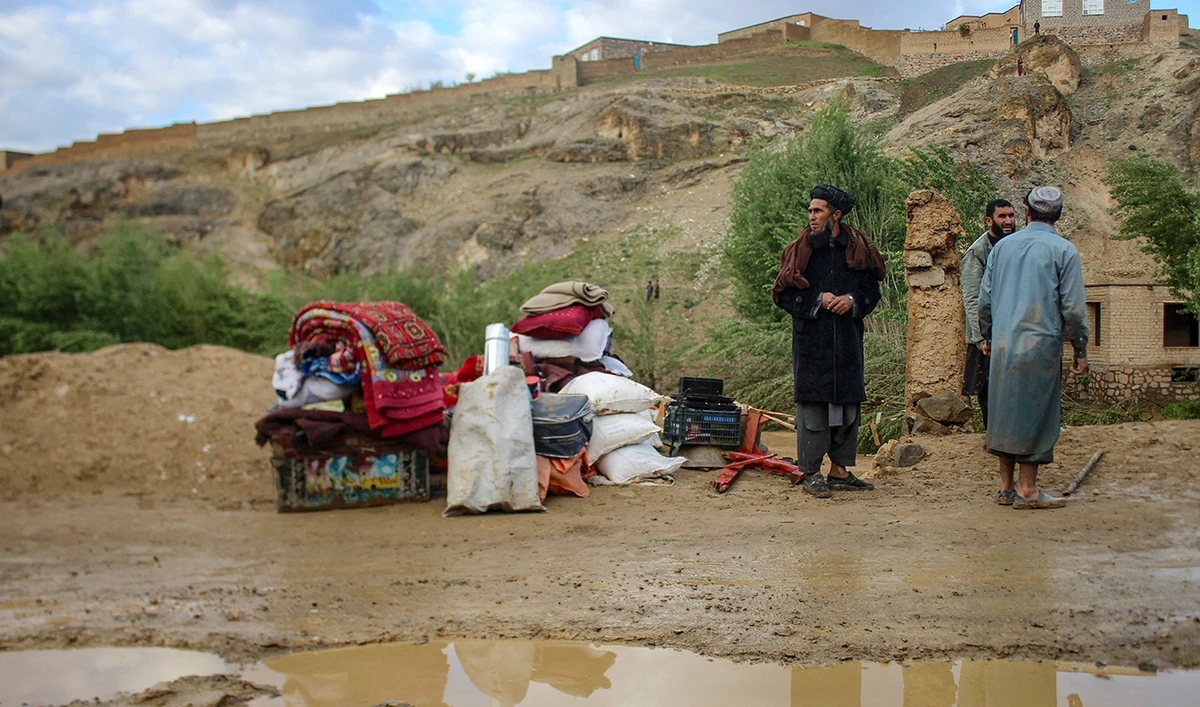 Afghan men stand beside their belongings kept near a damaged house after flash floods following heavy rainfall in Firozkoh, Ghor province on May 18, 2024. (AFP)