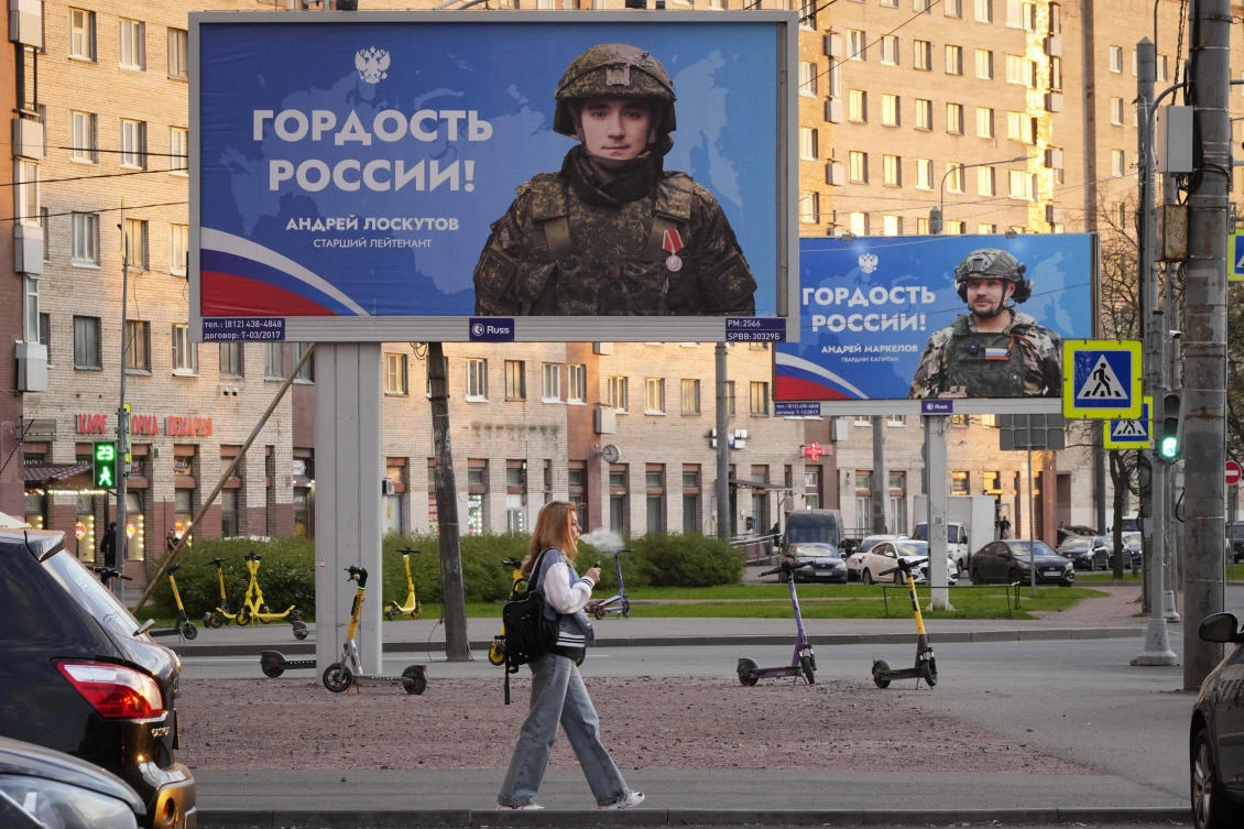 A woman walks past advertising billboards which show Russian soldiers, participants of military operation in Ukraine with words in Russian ‘Pride of Russia!’, in St. Petersburg on May 16, 2024. (AP)
