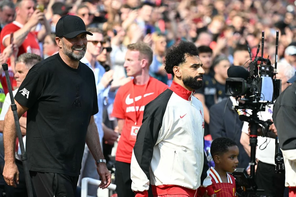 Liverpool’s German manager Jurgen Klopp walks out with Egyptian striker Mohamed Salah ahead of kick-off in the English Premier League match against Wolverhampton Wanderers at Anfield in Liverpool on May 19, 2024. (AFP)