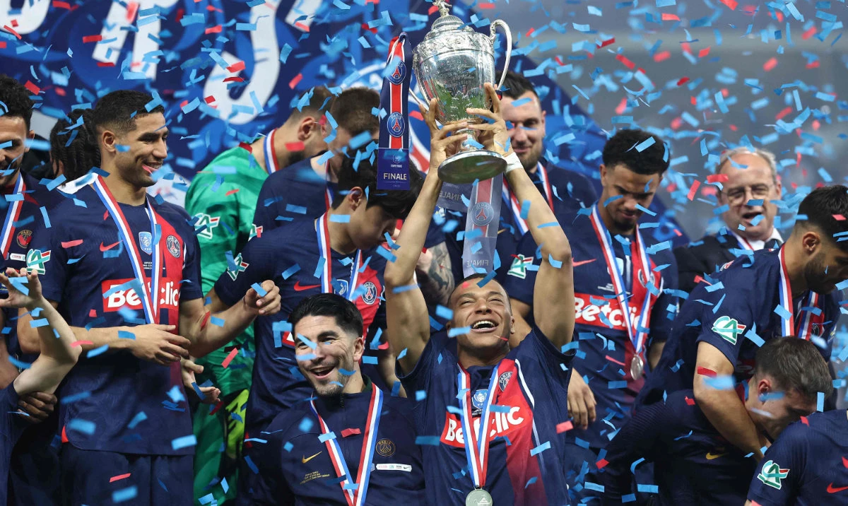 Paris Saint-Germain's French forward Kylian Mbappe (C) lifts the trophy as he celebrates with teammates on the podium after winning the French Cup final against Olympique Lyonnais at the Stade Pierre-Mauroy, in Villeneuve-d'Ascq, northern France on May 25, 2024. (AFP)