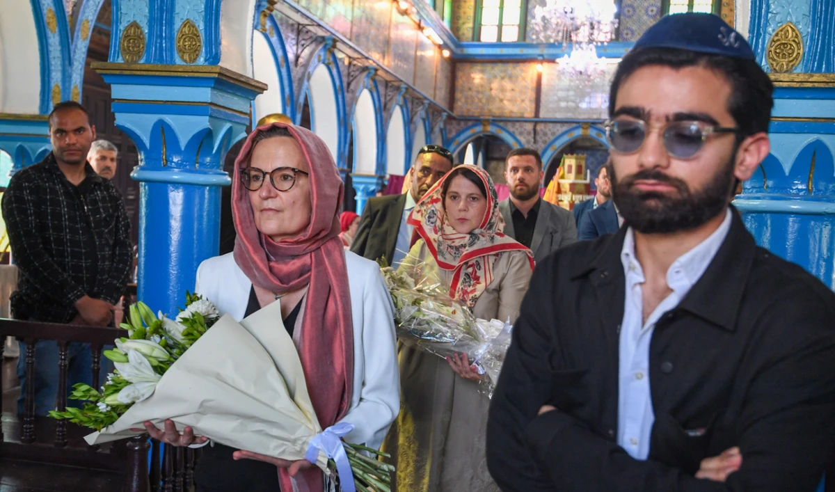 French ambassador to Tunisia Anne Gueguen (Centre-L) and US Deputy Chief of Mission Natasha Franceschi (C) carry flowers in memory of those killed in a mass shooting last year at the Ghriba synagogue in Djerba, during the second day of the annual Jewish pilgrimage on May 26, 2024. (AFP)