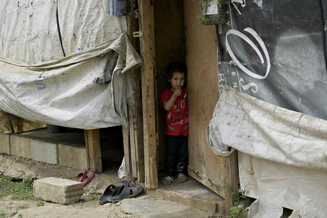 A Syrian refugee girl stands at the door of her family’s tent at a camp set up outside the northern Lebanese village of Miniara, in the area of Akkar near the border with Syria, on May 20, 2024. (AFP)