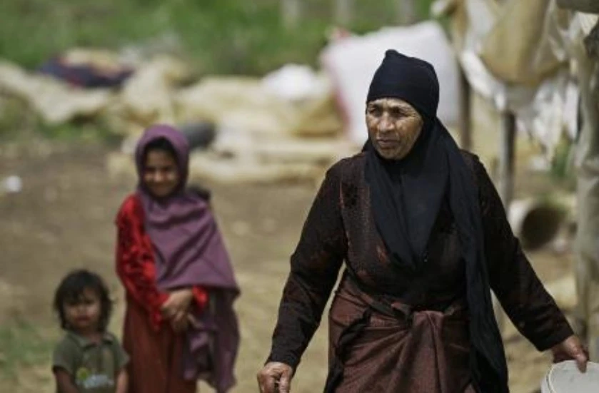 Syrian refugee children walk behind a woman at a camp set up outside the northern Lebanese village of Miniara, in the area of Akkar near the border with Syria, on May 20, 2024. (AFP)