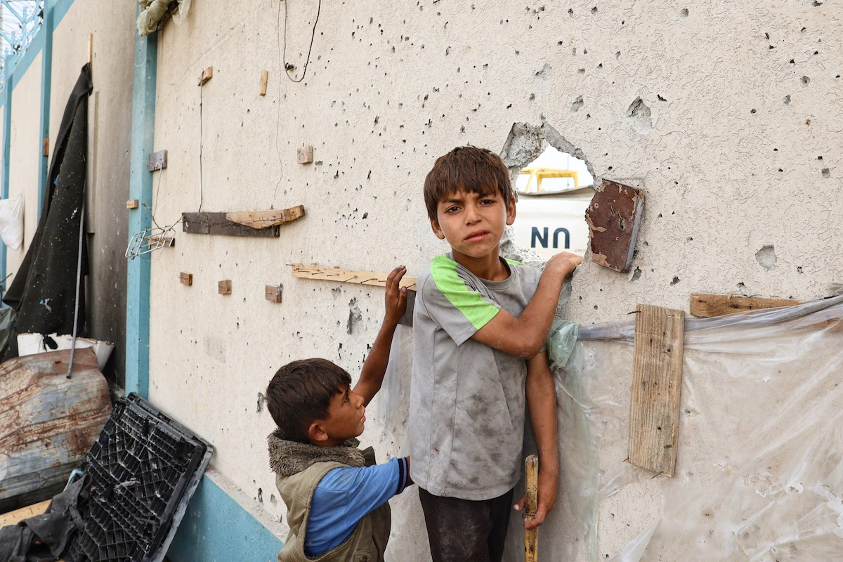 Palestinian boys stand near a damaged structure at the site of an Israeli strike a day earlier on a camp for internally displaced people in Rafah in the southern Gaza Strip on May 28. (File/AFP)