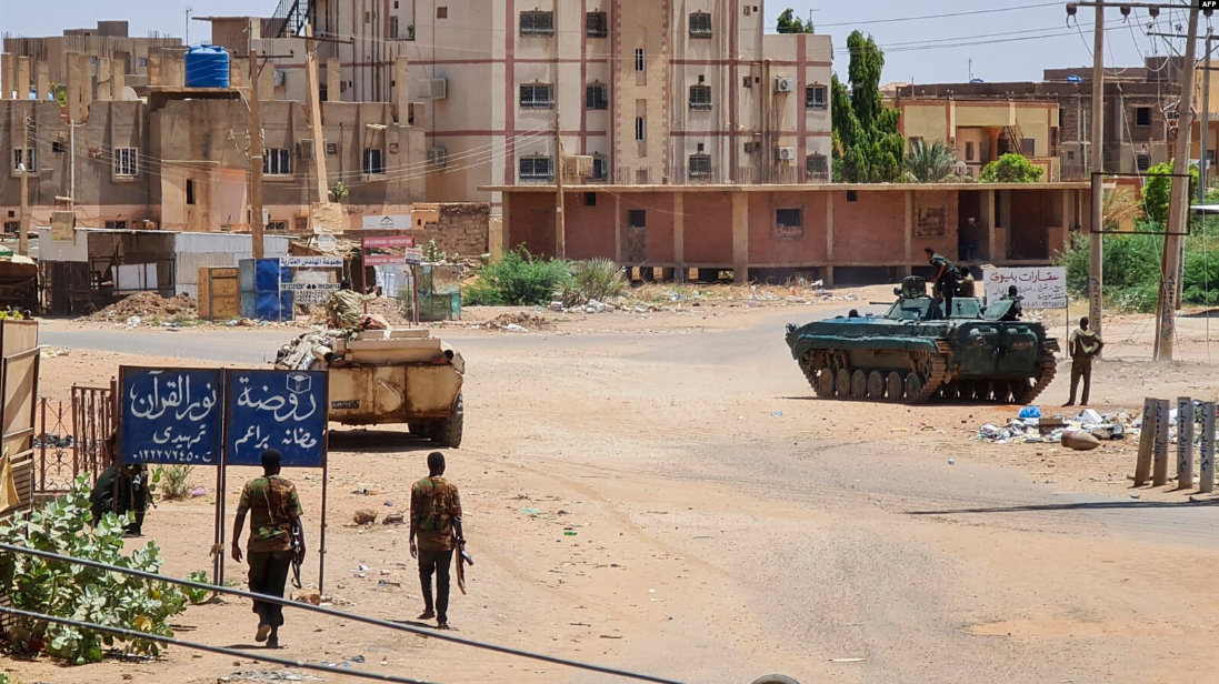 Sudanese Army soldiers walk near armored vehicles positioned on a street in southern Khartoum. (AFP)