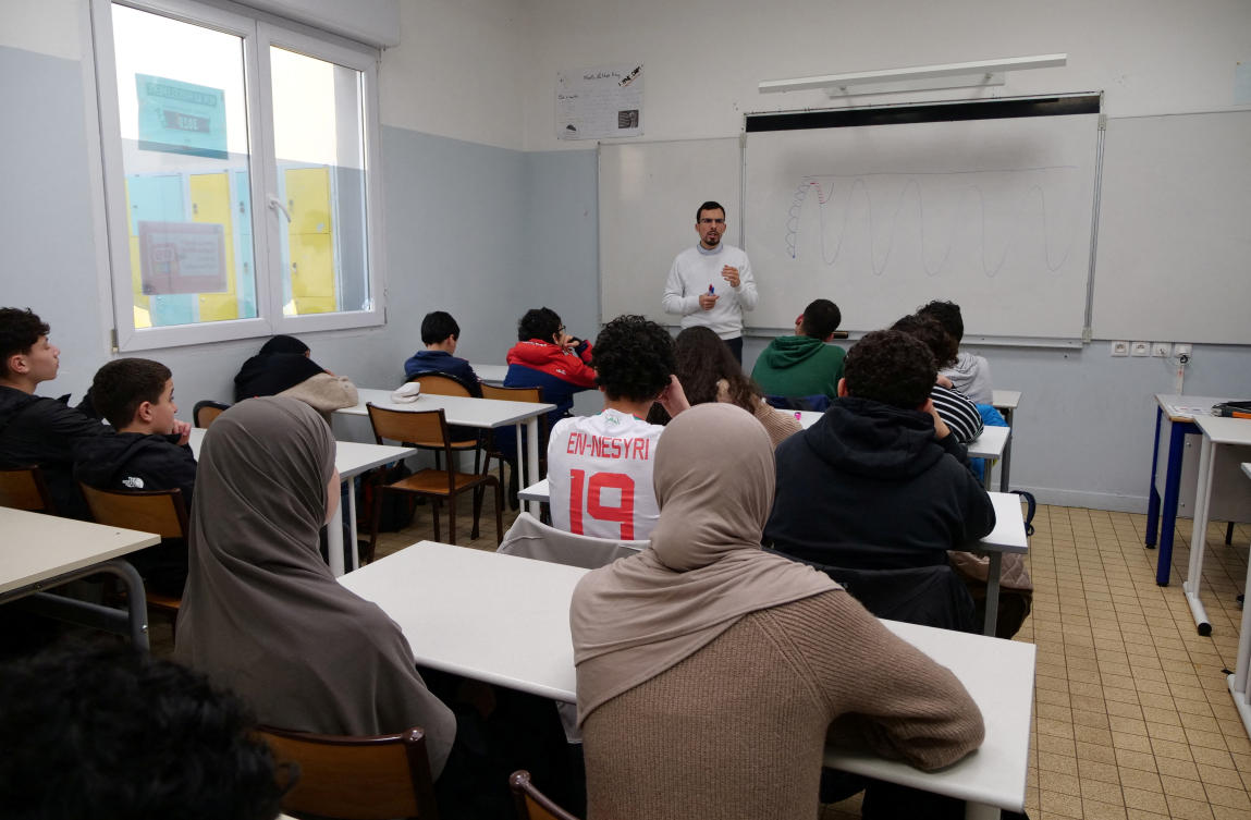Middle school students, some wearing a hijab, listen to teacher Ilyas Laarej during an Islamic ethics class at the Averroes school, France's biggest Muslim educational institution that has lost its state funding on grounds of administrative failures and questionable teaching practises, in Lille, France, March 19, 2024. (Reuters)