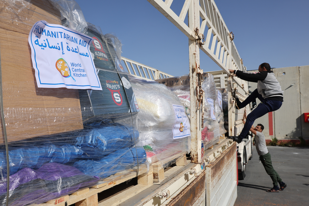 Truck drivers refasten a humanitarian aid cargo after inspection by Israeli security upon arriving from Egypt on the Israeli side of the Kerem Shalom border crossing, before entering the southern Gaza Strip. (File/AFP)