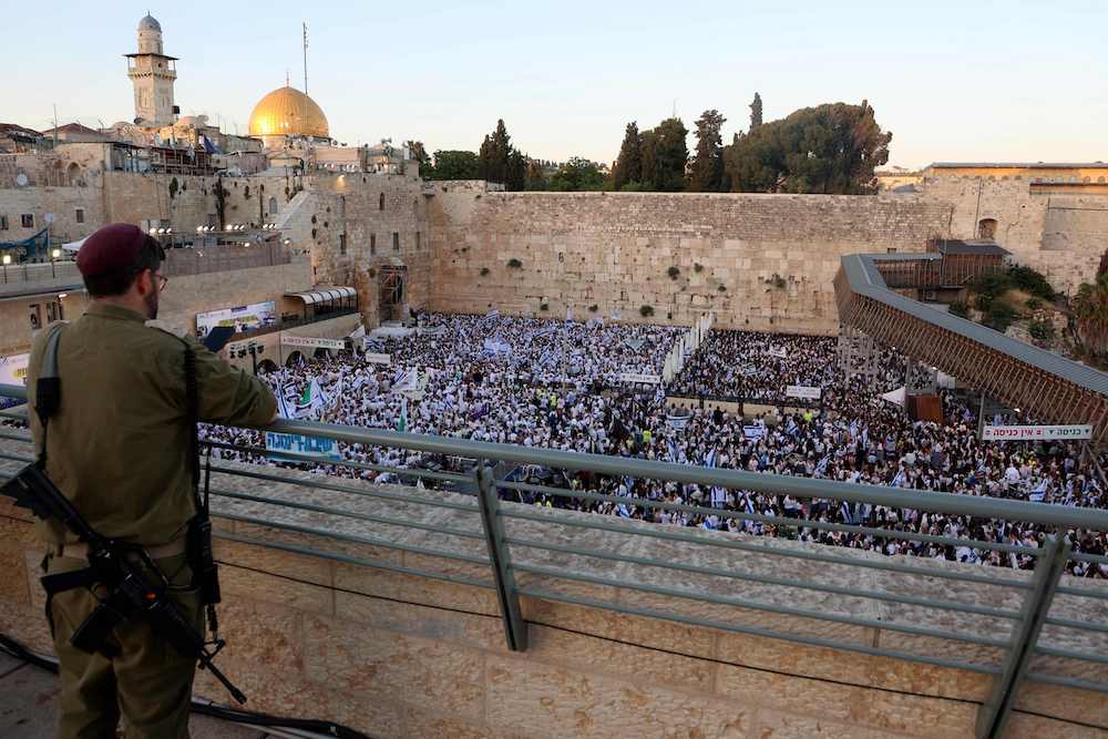 An armed Israeli soldier watches nationalists gathered at the Western Wall in the Old City of Jerusalem on June 5, 2024, during the so-called Jerusalem Day flag march. (AFP)An armed Israeli soldier watches nationalists gathered at the Western Wall in the Old City of Jerusalem on June 5, 2024, during the so-called Jerusalem Day flag march. (AFP)