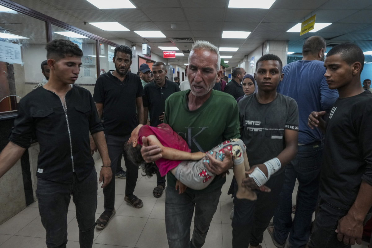 A Palestinian man brings a child wounded in the Israeli bombardment of the Gaza Strip into a hospital in Deir al Ballah on June 5, 2024. (AP)