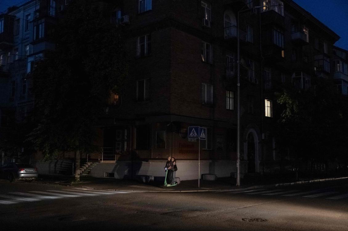 A young woman rides a scooter in a non-illuminated street during a partial electricity blackout in Kyiv on June 6, 2024, following Russian strikes on Ukrainian energy infrastructure, amid the Russian invasion of Ukraine. (AFP)