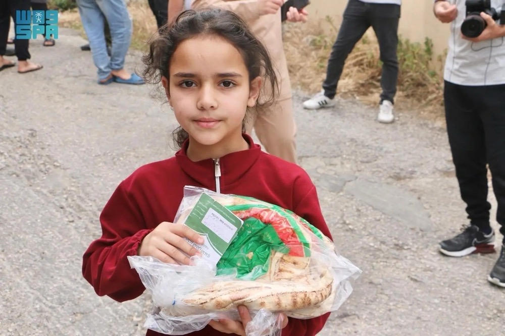A girl collects a KSrelief-provided bread pack in northern Lebabon. (SPA)
