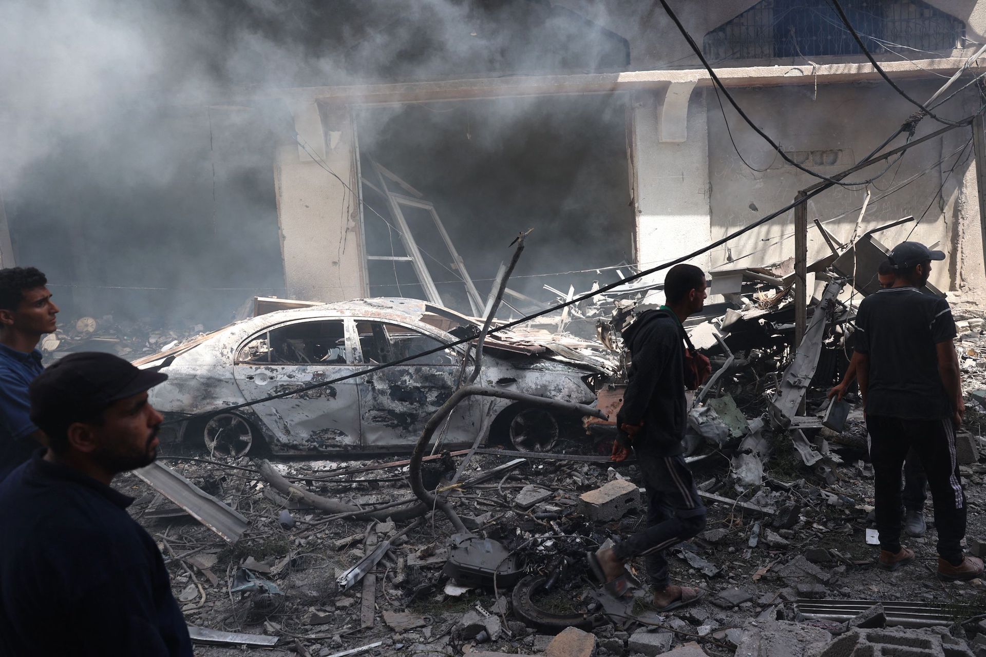 Palestinian men look at the destruction following an operations by the Israeli Special Forces in the Nuseirat camp, in the central Gaza Strip on June 8, 2024. (AFP)