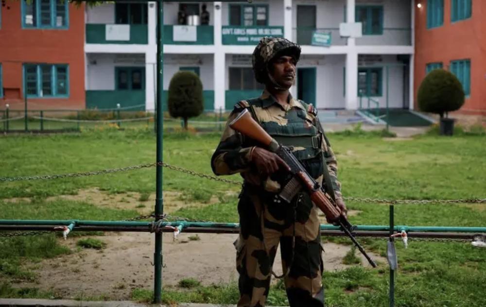 A security personnel stands guard outside a polling station, during the fourth general election phase, in south Kashmir’s Pulwama district, May 13, 2024. (Reuters)