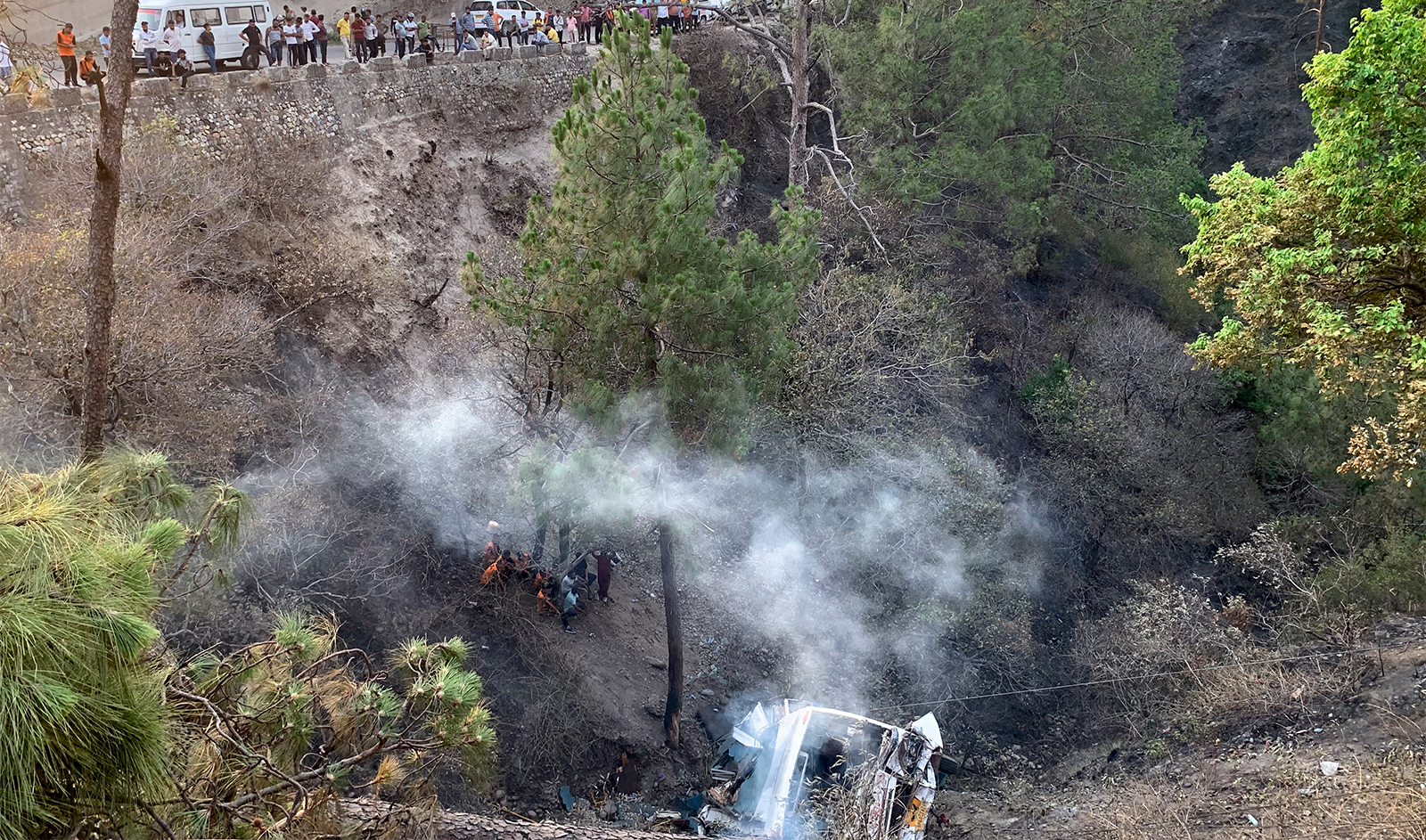 Members of a rescue team gather near a damaged bus lying in a forested area after it collapsed into a ravine in Akhnoor on May 30, 2024. (AFP/File)
