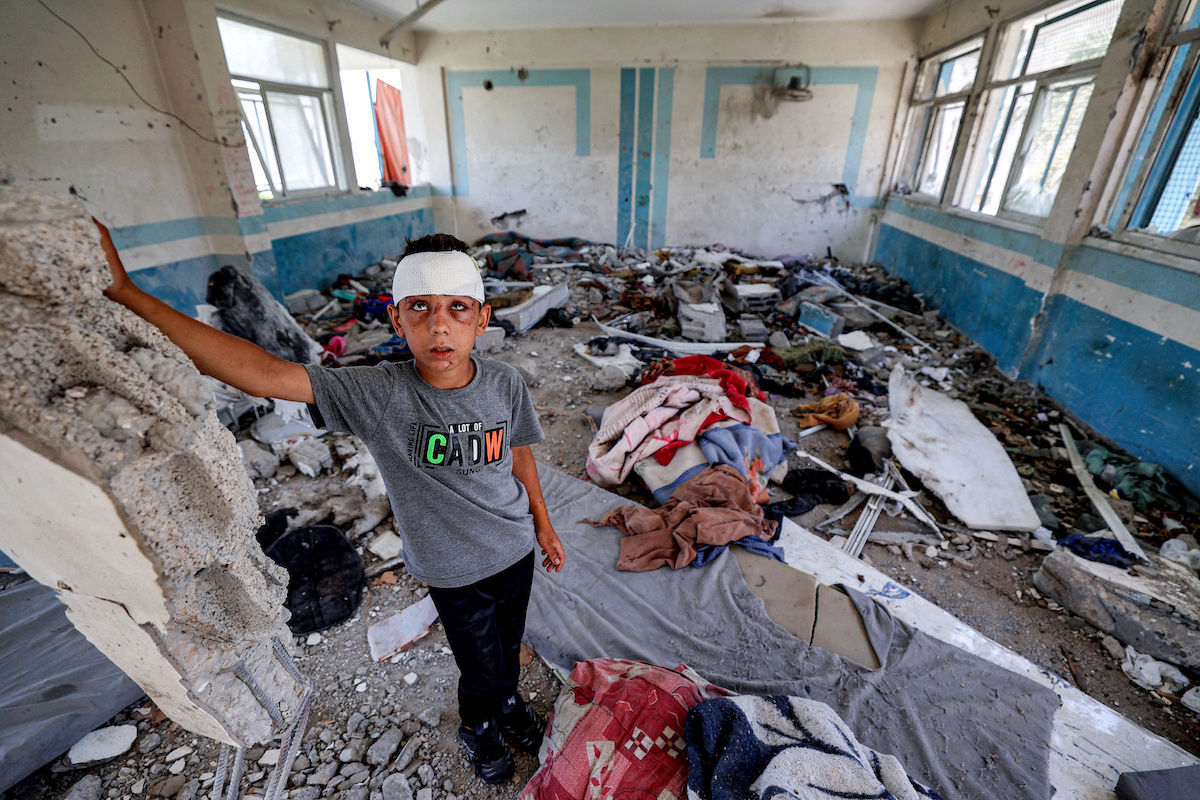 An injured boy stands in a destroyed classroom where mattresses were laid out for people sheltering there at a school run by UNRWA that was hit by Israeli bombardment, in the Nuseirat camp in Gaza. (File/AFP)