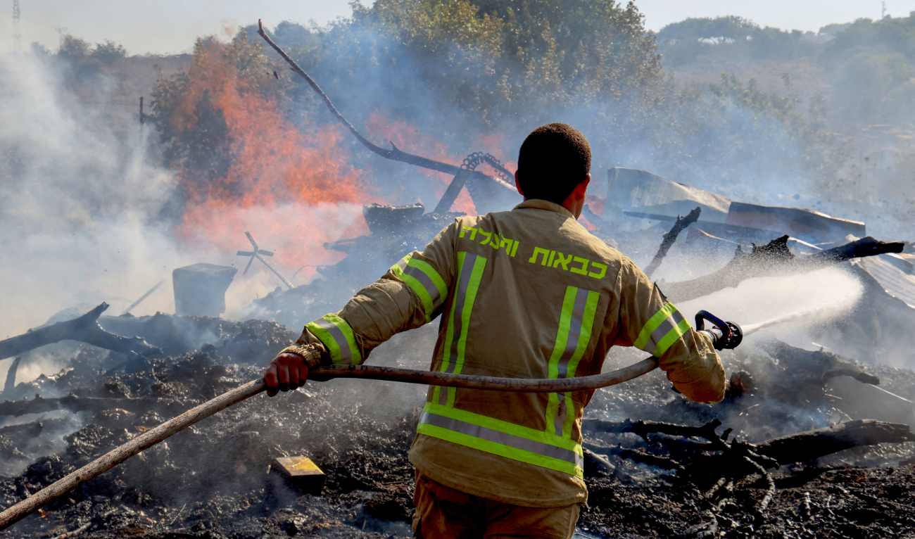 An Israeli firefighter puts out flames in a field after rockets launched from southern Lebanon landed on the outskirts of Kiryat Shmona, on June 4, 2024. (AFP/File)