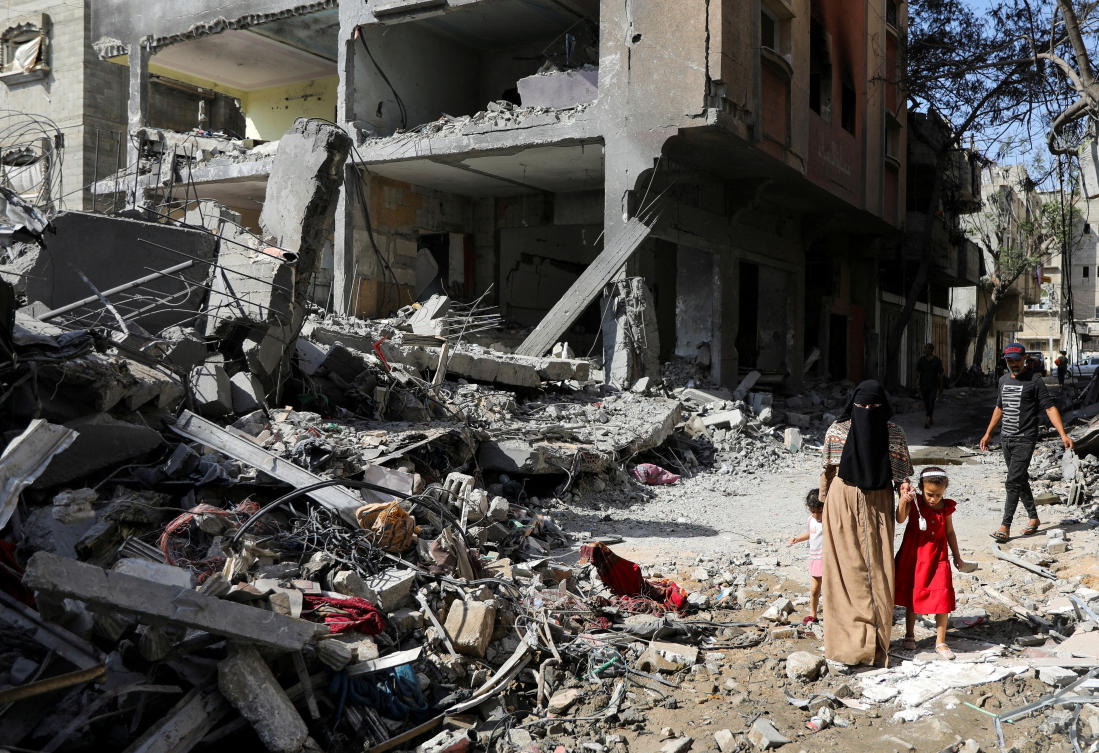 A woman and child walk among debris, aftermath of Israeli strikes at the area, where Israeli hostages were rescued on Saturday, as Palestinian death toll rises to 274, amid the Israel-Hamas conflict, in Nuseirat refugee camp in the central Gaza Strip, June 9, 2024. (Reuters)