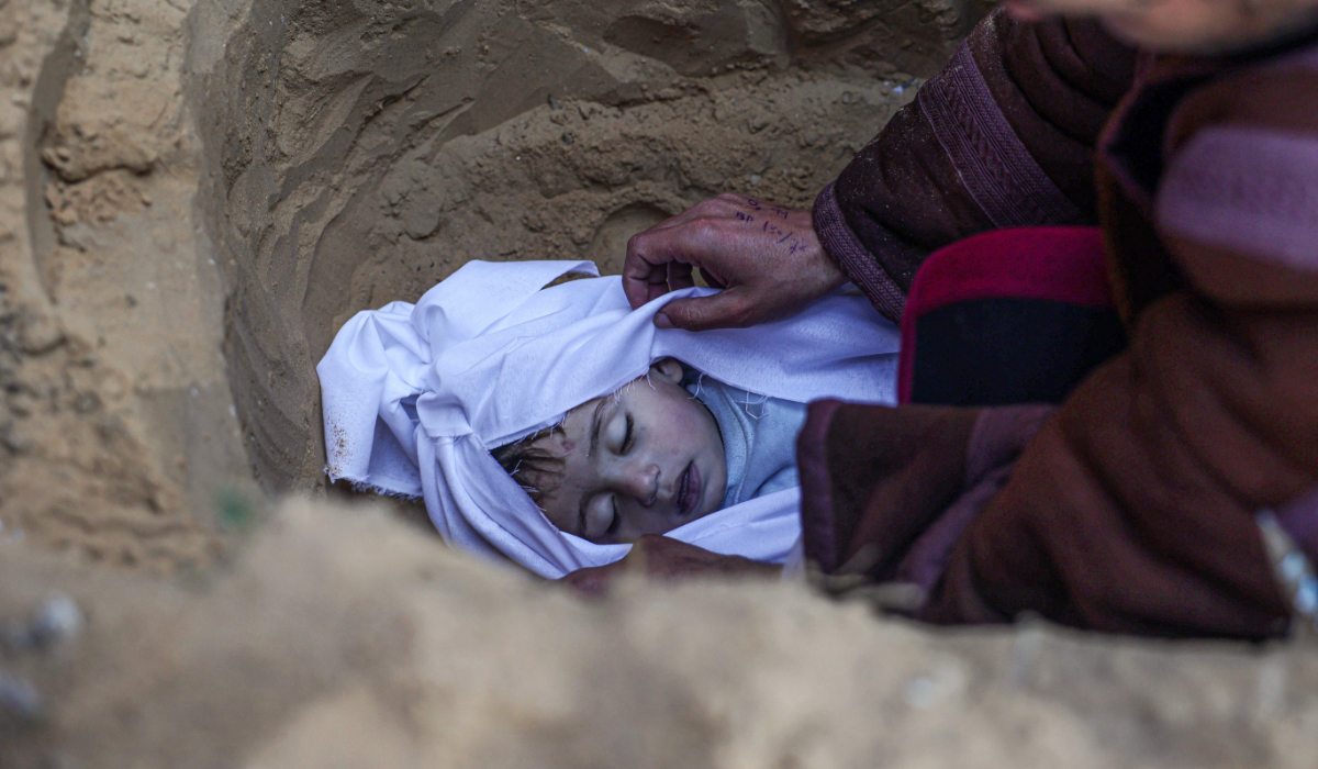 A man buries his child who was killed in overnight Israeli air strikes on the Moammar home, at a cemetery in east Khan Yunis in the southern Gaza Strip on February 26, 2024, amid ongoing battles between Israel and the militant Hamas movement. (AFP)