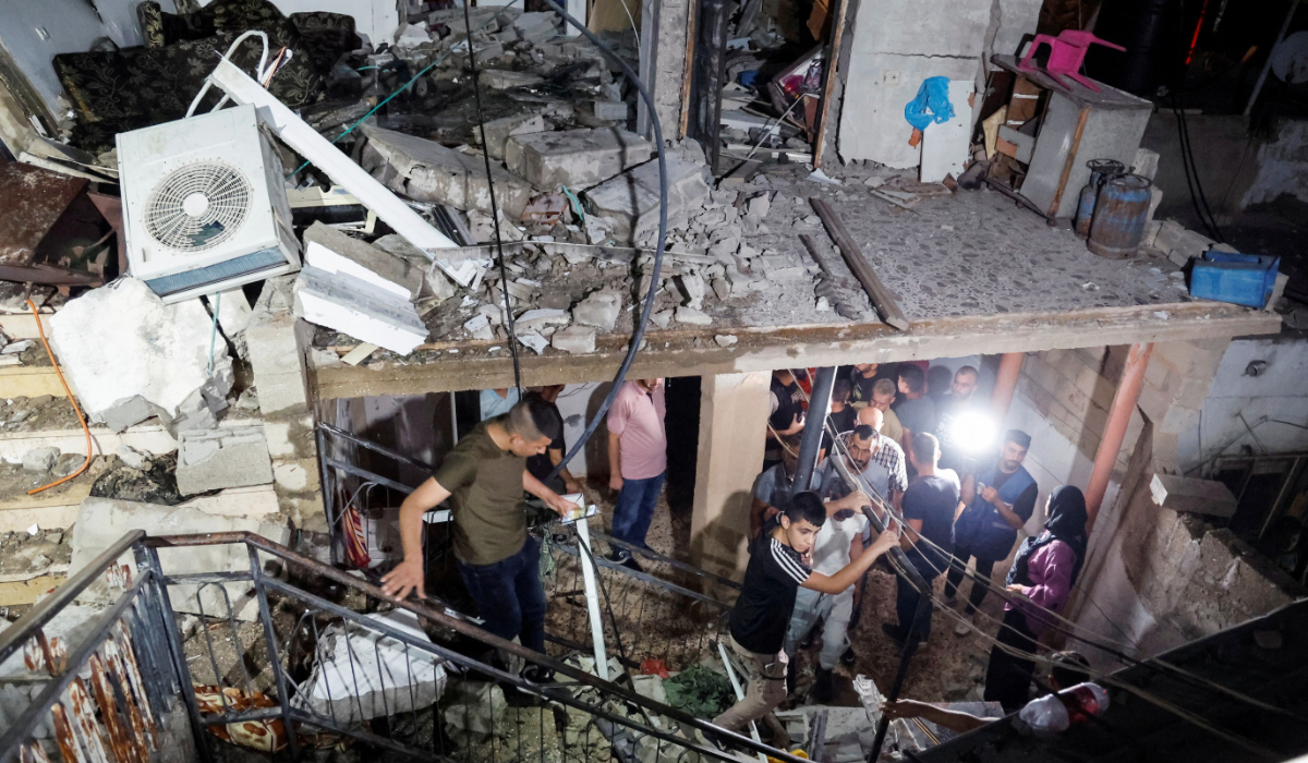 People walk in a damaged building targeted by Israeli forces during a raid in which Palestinians were killed, in Kafr Dan, near Jenin, in the Israeli-occupied West Bank June 11, 2024. (REUTERS)