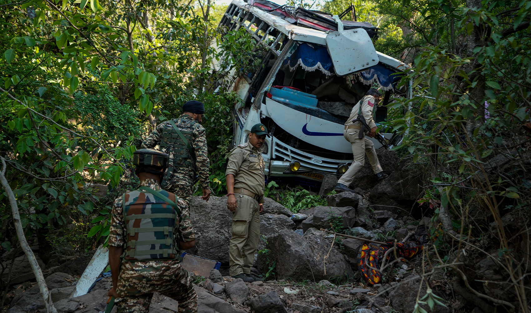 Security men inspect a bus that fell into a deep gorge on Sunday after it was fired at by suspected militants in Reasi district, Jammu and Kashmir, on June 10, 2024. (AP)