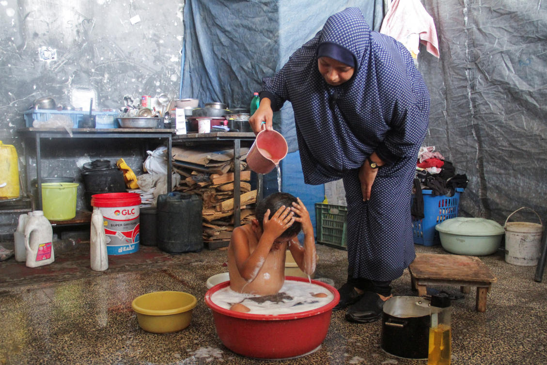 A displaced Palestinian woman bathes her son as Gazan families struggle with water pollution and scarcity, amid the ongoing conflict between Israel and Hamas, in Jabalia refugee camp, in the northern Gaza Strip.(REUTERS)