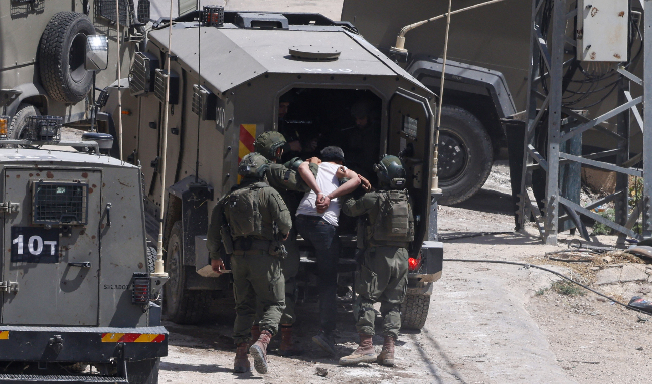Israeli soldiers detain a Palestinian man during a raid in the occupied West Bank town of Deir Al-Ghusun near Tulkarem on May 4, 2024. (AFP/File)