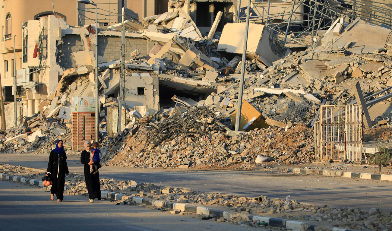 Displaced Palestinians walk past destroyed buildings in al-Bureij refugee camp in the central Gaza Strip on June 12, 2024. (AFP/File)