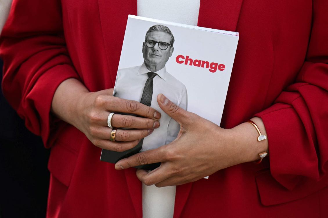A member of Britain's main opposition Labour Party poses with the Labour Party election manifesto booklet during its launching, in Manchester, on June 13, 2024 in the build-up to the UK general election on July 4. (AFP)