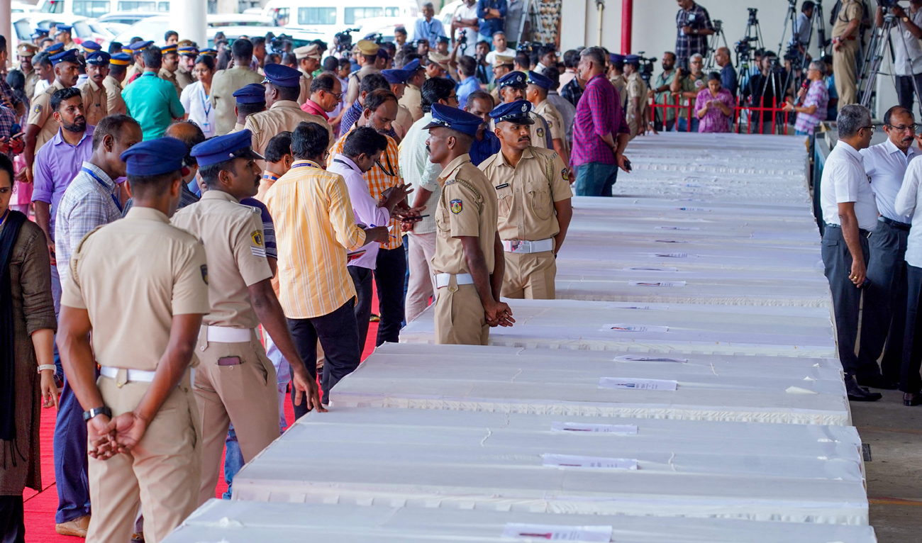 Policemen stand guard as mourning relatives await coffins of the deceased arriving on an Indian Air Force plane from Kuwait at the Cochin International Airport in Kochi on June 14, 2024. (AFP)
