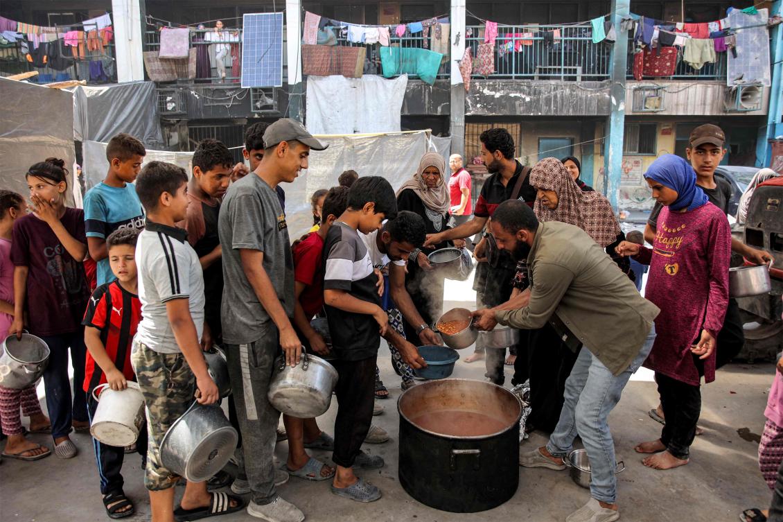 Children queue with pots to receive food aid from a kitchen at the Abu Zeitun school run by UNRWA in the Jabalia camp for Palestinian refugees in the northern Gaza Strip on June 13, 2024. (AFP)