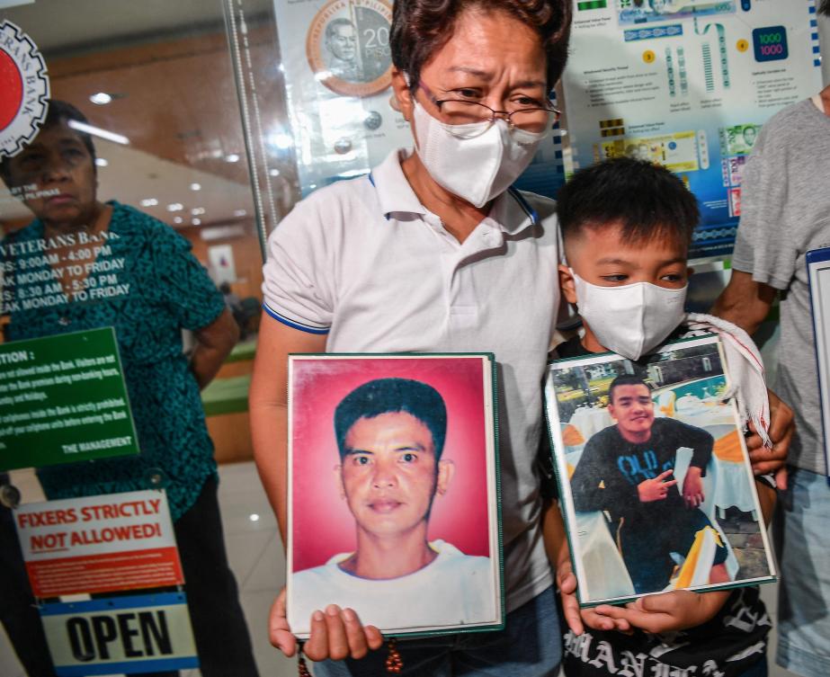 Mary Ann Domingo, center, and her son hold portraits of her husband and son after four policemen were found guilty of killing them during their trial at a court in Manila on June 18, 2024. (AFP)